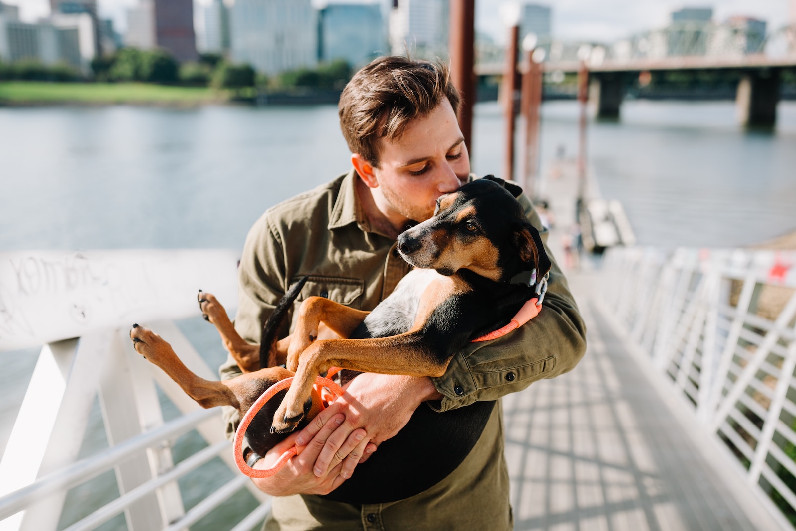 Dutchess County SPCA man in brown jacket hugging black and brown short coated dog