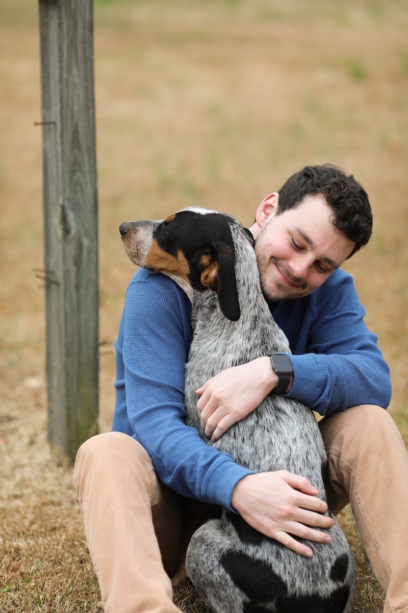 Orange County Animal Shelter man in purple jacket holding black and white short coated dog